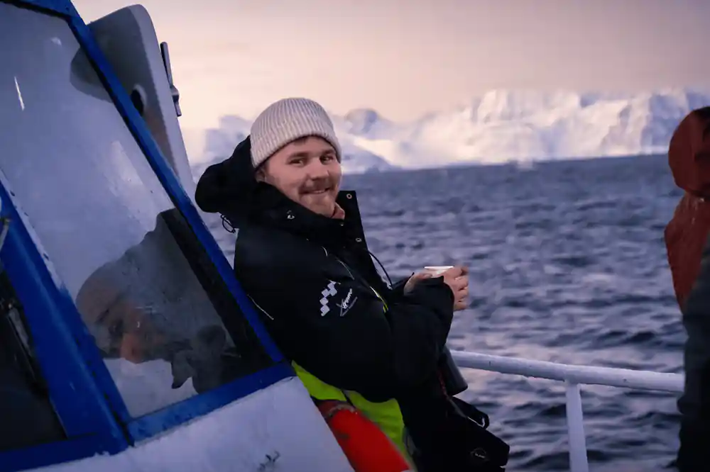A crew member at the wheelhouse door with a hot drink
