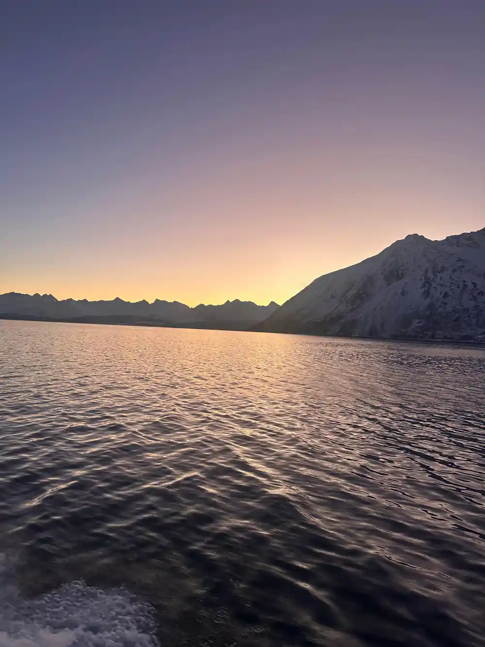 A low sun behind a headland with the fjord in shadow
