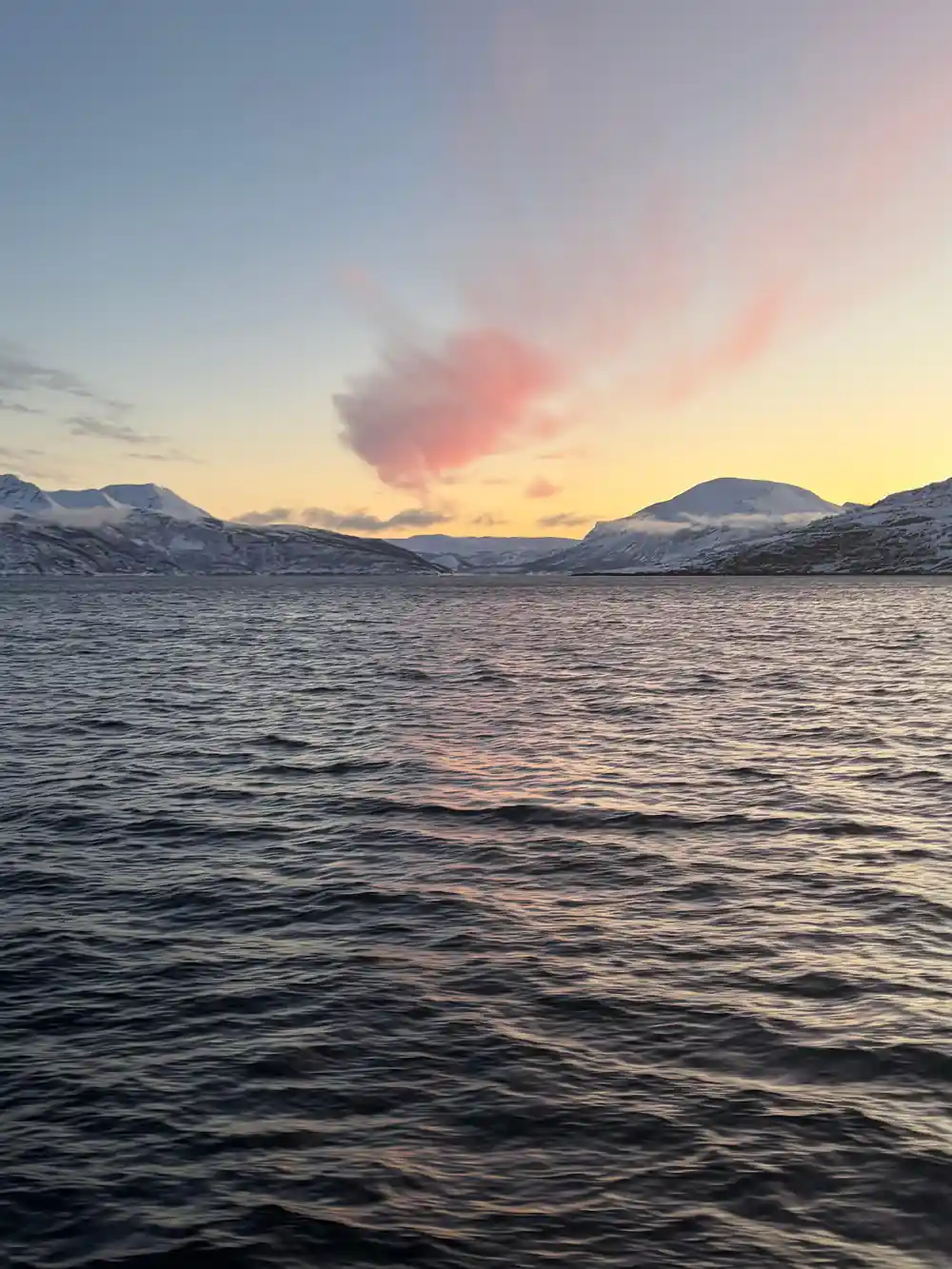 A pink cloud burning over the ridge line at sunrise