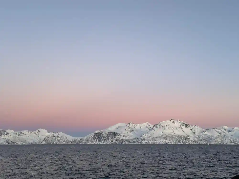 A snow ridge under a wide pink and blue winter sky